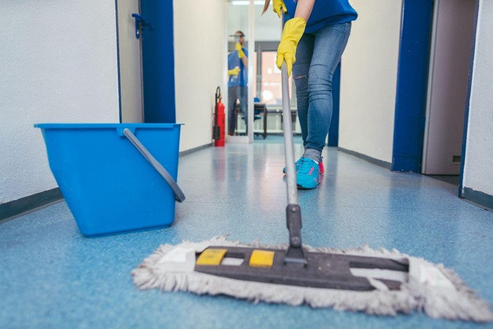Cleaning professional mopping office hallway with blue bucket, emphasizing post-construction cleaning for a safe and inviting workspace.